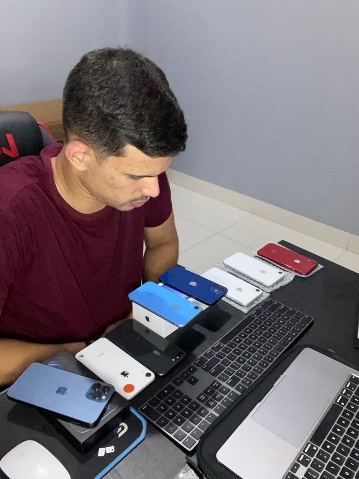 Tyago Sena conferindo uma fileira de iPhones na mesa de trabalho